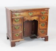 An 18th century mahogany kneehole desk, with brushing slide over cupboard door with an arrangement