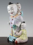 A Chinese famille rose enamelled group of children, Republic period, the central figure holding a