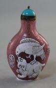 A Chinese white overlaid glass snuff bottle, carved in relief with a bird perched on a lion-dog