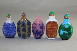 Five Chinese overlaid glass snuff bottles, in various colours, one decorated with figures in green