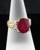 A modern 18ct gold, ruby and diamond set dress ring, the central oval cut ruby flanked by six