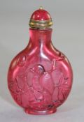 A Chinese pale ruby glass snuff bottle, carved in relief with birds perched in trees and fish