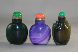 Three Chinese stained agate snuff bottles, two in purple and green, the last in green carved with