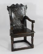 A 17th century joined oak Wainscot chair, with scrolling carved top rail and carved central panel,