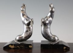 A pair of 20th century figural bookends modelled as two silvered sea lions, on marble bases, the