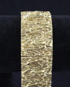 A late 1960`s 9ct gold bark effect hinged panel bracelet, 7.5in 102 grams.