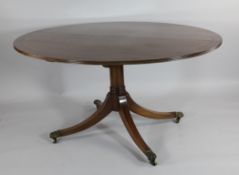 An Edwardian Howard & Sons oval mahogany dining table, on gun barrel support and four scroll legs