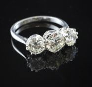 An 18ct white gold and platinum set three stone diamond ring, with pierced scroll setting, total