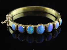An Edwardian gold and seven stone graduated opal set stiff bracelet.
