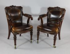 A pair of Victorian mahogany brown leather and brass studded library chairs, with open arms and