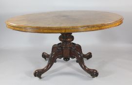 A Victorian oval walnut loo table, with central carved column and four scroll legs, W.5ft