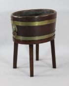 A 19th century oval brass bound wine cooler, with lion mask ring handles, on an oak base, W.1ft