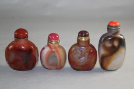 Four Chinese chalcedony or agate snuff bottles, three of flattened flask form, one with carved