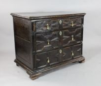 A late 17th century oak chest, with four long geometrically fielded panelled drawers, on later