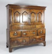 A mid 18th century oak cupboard, with two panelled doors above five drawers, on bracket feet, 4ft