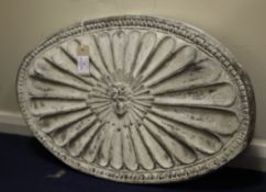 A lead oval plaque, centered with a sunburst mask, 25.25ins