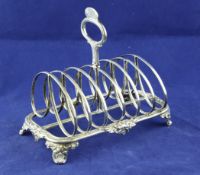 An early Victorian silver seven bar toast rack, with floral decoration and ring handle, on scroll