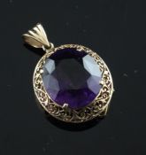 A Victorian style gold and amethyst pendant, the oval cut stone set within a pierced scroll