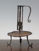 An iron adjustable candle holder, 17th / early 18th century, the wavy edged drip pan rising to