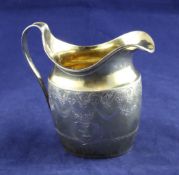 A George III silver gilt cream jug, of oval form, with engraved armorials and decorated with