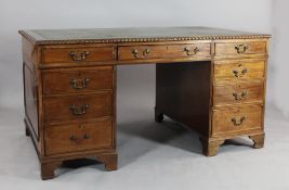 An Edwardian carved mahogany pedestal desk, with leather insert top above an arrangement of nine