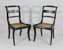 A pair of Regency ebonised and brass mounted dining chairs, with caned seats on sabre legs