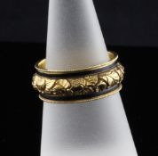 An early 19th century gold and black enamel memorial ring, with floral chased band within two