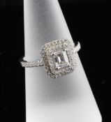 An 18ct white gold and diamond cluster ring, of rectangular shape, the central emerald cut stone
