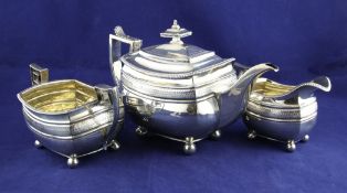 A George III silver three piece tea set, of shaped oblong form, with engraved band, gadrooned border