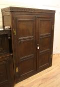 An 18th century carved oak robe cupboard, with two panelled doors, on stile feet, 5ft 11in. x 4ft
