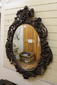 A 19th century carved and stained wood oval mirror, decorated with fruit and flowers, 3ft 10ins x