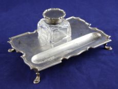 A George V silver inkstand, of shaped rectangular form, with single mounted glass well and pen
