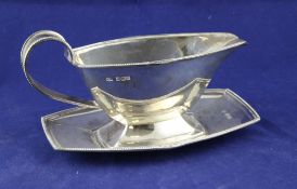 A 1930`s Art Deco silver sauceboat and stand, with fan decorated milled rim on conforming