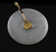 A 14ct gold mounted jadeite disc pendant, the central boss with Chinese characters, 2in.