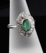 An 18ct white gold, emerald and diamond cluster ring, with central oval cut emerald bordered by