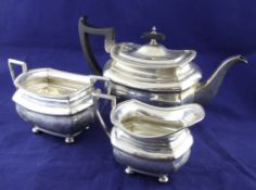 A George V silver three piece tea set, of shaped rectangular form, with gadrooned borders, on ball