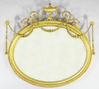 An Adam design carved giltwood and gesso oval wall mirror, with harebell swags and flaming urn