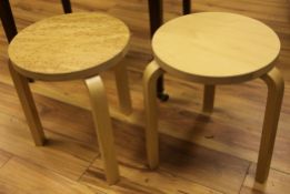 Two Artek Alvar Aalto design birchwood stools, with differing veneers to tops