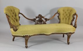 A Victorian carved walnut serpentine salon settee, with buttoned chair back and scroll end arms on