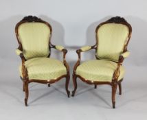 A pair of Victorian carved walnut salon chairs, with upholstered backs, seats and arms, on