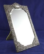 An Edwardian repousse silver rectangular easel mirror, with domed top and decorated with floral