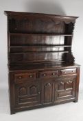 A mid 19th century oak dresser, the boarded, canopied back with three shelves over an arrangement of