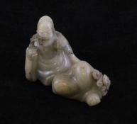 A Chinese cream coloured soapstone figure of a reclining Luohan, holding a sprig of lingzhi, 3.