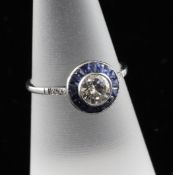 A platinum, diamond and sapphire cluster ring, with diamond set shoulders and central brilliant