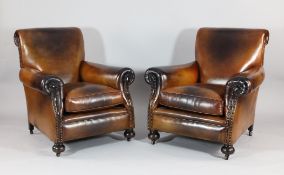 A pair of Edwardian tan leather club chairs, on stained wood ball feet