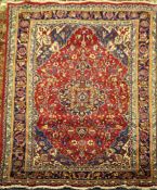 An Iranian carpet, with central medallion within a shaped field of scrolling foliage, on a red, blue
