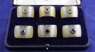 A cased set of six late Victorian silver mounted gem set horn napkin rings, each ring set with an