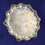 An Edwardian silver circular salver, with scroll and shell decorated rim, on claw and ball feet,