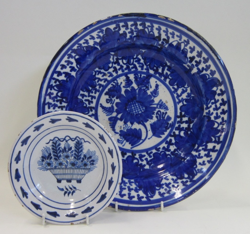 A twin glazed earthenware charger, painted in blue with floral motifs and borders; together with a