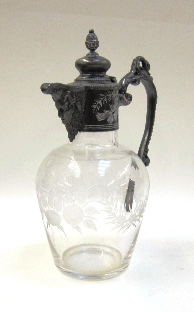 A base metal mounted glass Claret Jug. The glass body well engraved with butterflies and foliate